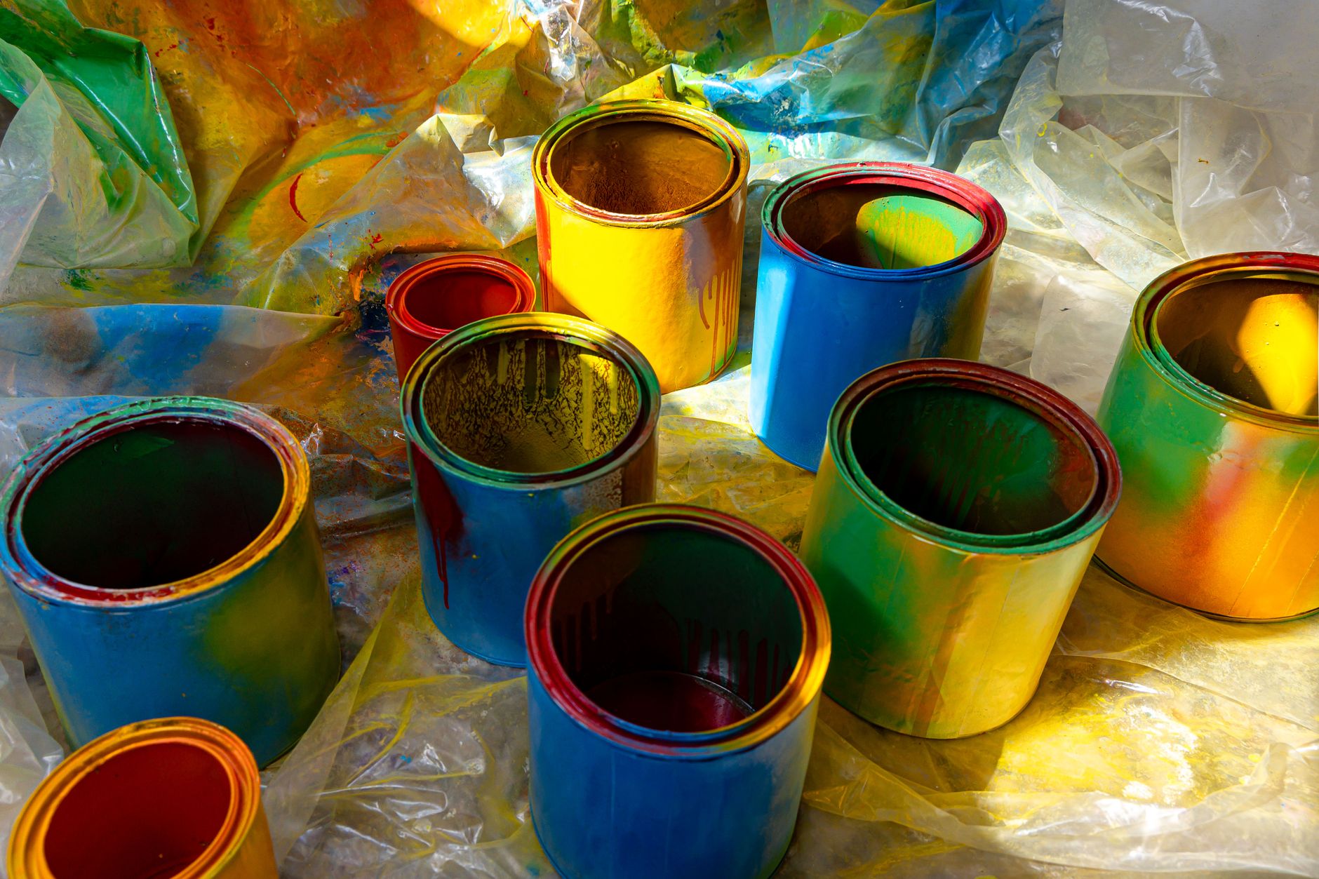 Colorful open paint cans on a plastic sheet with vibrant colors spilling over. Perfect for art and DIY themes in Torrance, CA
