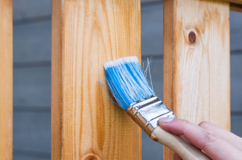Hand painting a wooden plank with a brush